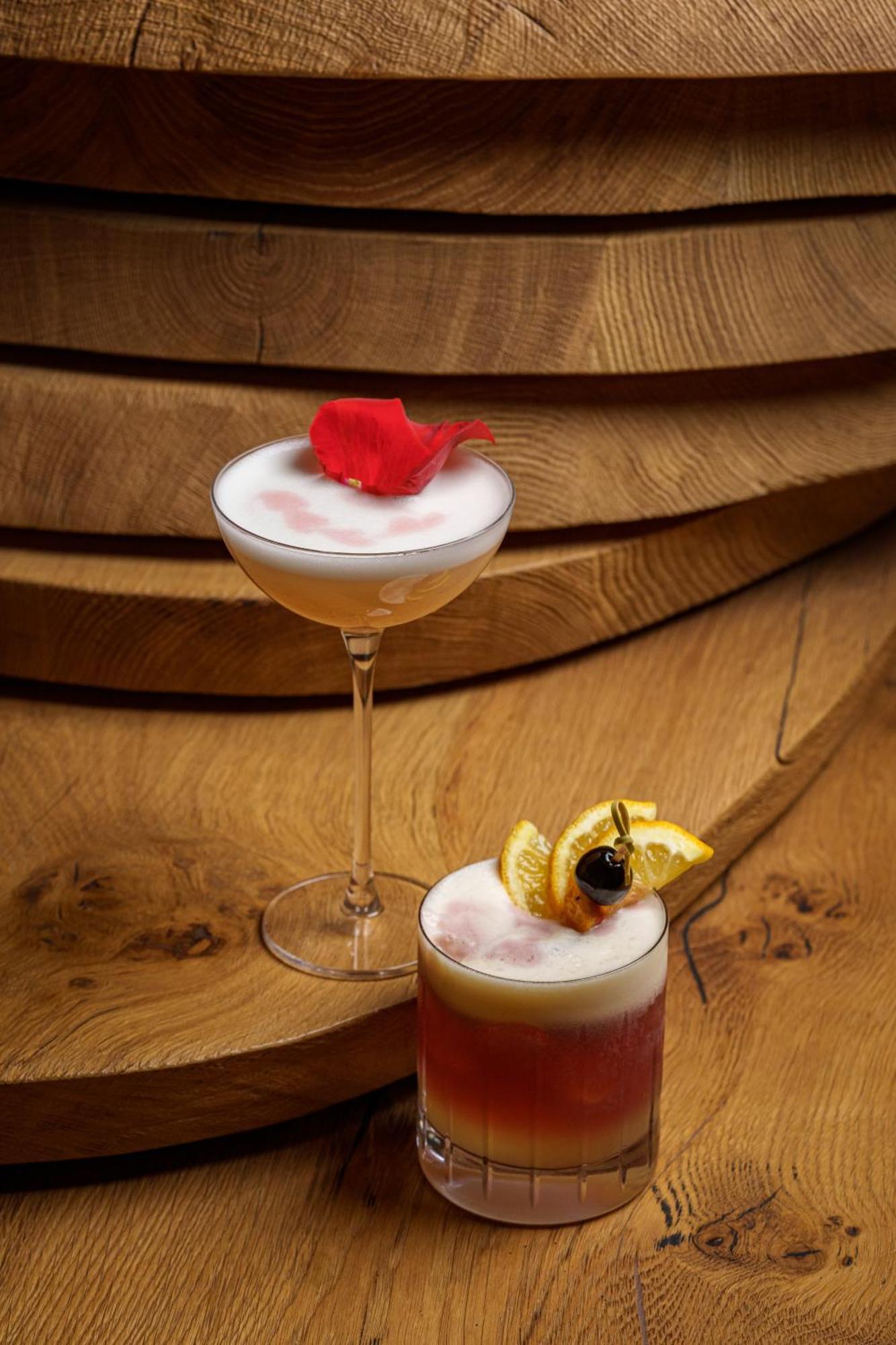 Middle Eight - Covent Garden - Preferred Hotels And Resorts 伦敦 外观 照片 The photo showcases two elegant cocktails arranged against a warm wooden backdrop. 

1. The first cocktail is served in a classic coupe glass. It has a frothy, pale hue, topped with a vibrant red flower petal, adding a touch of sophistication. 

2. T